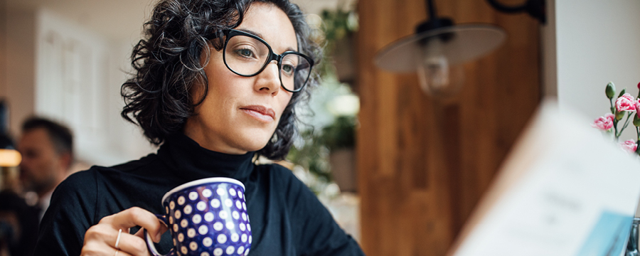 Businesswoman drinking coffee and reading a newspaper.