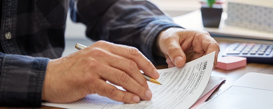 Hands holding pen and tax documents